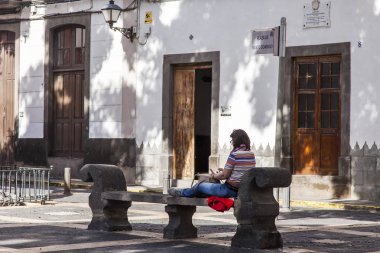 Las-Palmas de Gran Canaria, İspanya, 5 Ocak 2018. şehir merkezinde güzel bir sokak. İyi bir kadın bankta dinleniyor.