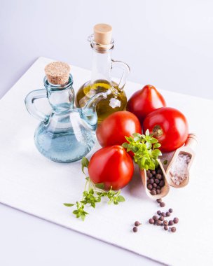 Taze salata pişirmek için gerekli malzemeler: domates, deniz tuzu, fesleğen, biber ve yağ ve sirke kabı.