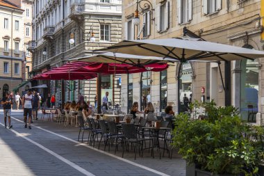 Trieste, İtalya, 5 Ağustos 2019. şehrin tarihi bölümünde pitoresk bir caddenin kaldırımda çekici kafe masaları.
