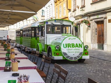 Ljubljana, Slovenya, 5 Ağustos 2019. Pitoresk şehir manzarası. Şehrin tarihi bölümünde güzel sokak, turistik elektrikli tren sokak kafe ile gider