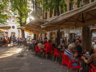 Trieste, İtalya, 5 Ağustos 2019. Tarihi şehirde pitoresk bir caddenin kaldırımında çekici kafe masaları.