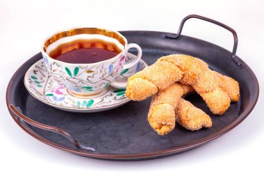 İştah açıcı kurabiyeler ve çay kaliteli metal bir tepside güzel bir porselen fincanda.