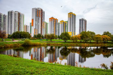 Saint Petersburg, Rusya, 13 Ekim 2020. Sonbahar manzarası. Çok katlı modern binalar ve portakal ağaçları göletin sularını yansıtıyor.