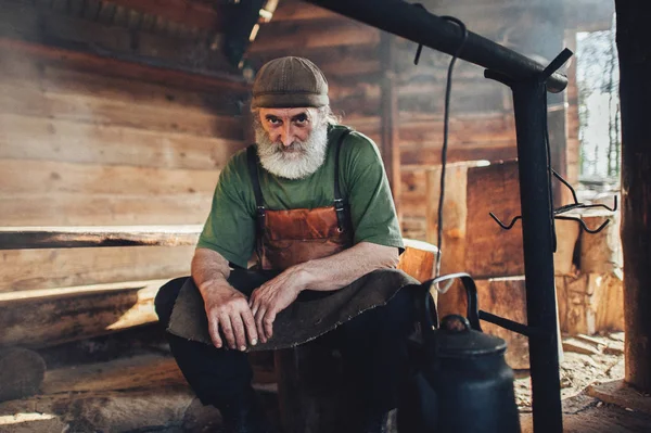 Old beard forester in dickey sitting in barn