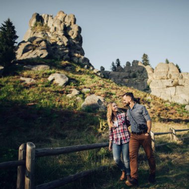 Genç neşeli hipster çift hafta sonları yeşil dağlarda günbatımı zevk.