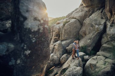Gün batımında romantik genç çift dağ arasında sarılma kayalar 