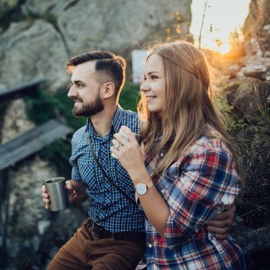 Genç sıcak çay içme gün batımında dağlarda Çift