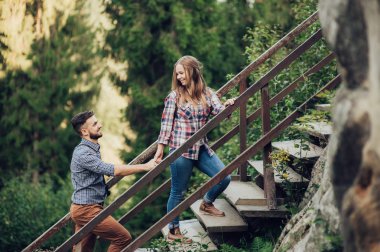 Genç çift günbatımında yeşil orman merdivenlerde yürürken