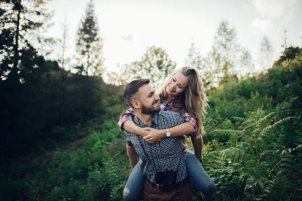 Junger Fröhlicher Mann Hält Freundin Huckepack Grünen Park Bei Sonnenuntergang — Stockfoto