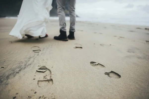 feet of wedding couple travelers standing on sandy Kvalvika beach, Norway