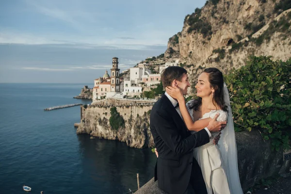 Portrait of young romantic couple with old coastal italian city on background