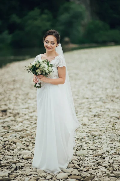 Noiva bonita com penteado e maquiagem posando com o buquê de casamento . — Fotografia de Stock