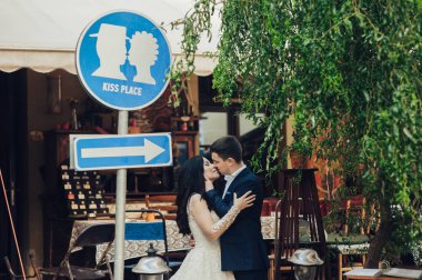 Mutlu genç gelin ve damat yol işareti Kissing yer yanında poz 
