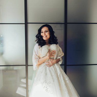 Young elegant bride preparing for wedding ceremony in hotel room 
