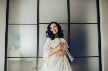 Young elegant bride preparing for wedding ceremony in hotel room 