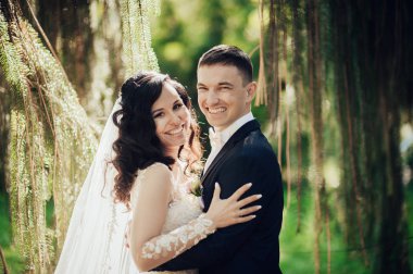 Gülümseyen mutlu gelin ve damat yeşil bahar parkta poz