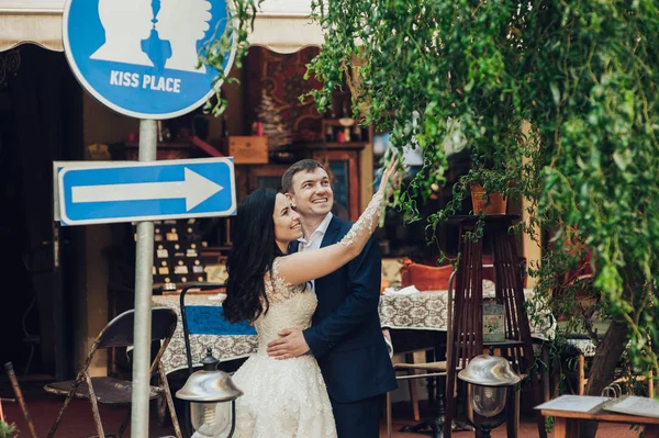 道路標識キス場所の横でポーズ幸せな若い花嫁と新郎 ロイヤリティフリーのストック画像