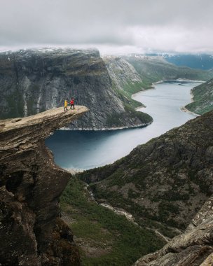 Norveç 'te Trolltunga' da iki turist duruyor. Güzel doğal tatil yürüyüşü doğa gezisi konsepti..