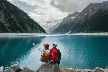 Gezginler dağ gölüne bakıyorlar. Sırt çantalı insanlar seyahat eder. Macera ve dağ bölgesinde seyahat. Zillertal Alpler, Avusturya.