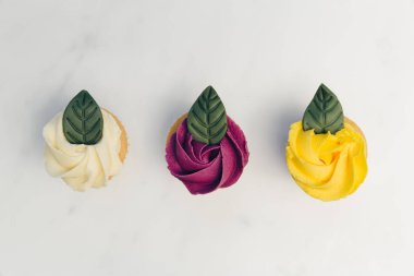 Beyaz mermer zemin üzerine gül çiçek cupcakes üstten görünüm