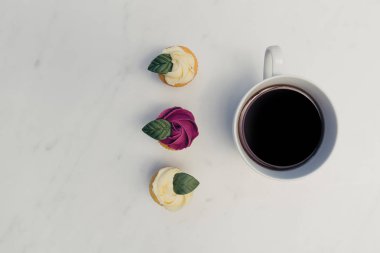 Kahve fincanı ile gül çiçek cupcakes üstten görünüm beyaz mermer zemin üzerine