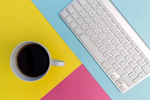 电脑键盘与咖啡在明亮的粉红色 黄色和蓝色背景 — 图库照片