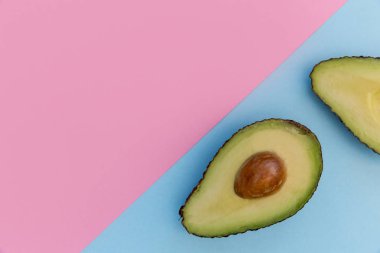 Parlak pembe bir arka plan üzerinde avokado yarım 