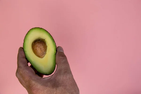 Hand Met Avocado Helft Helder Roze Achtergrond — Stockfoto