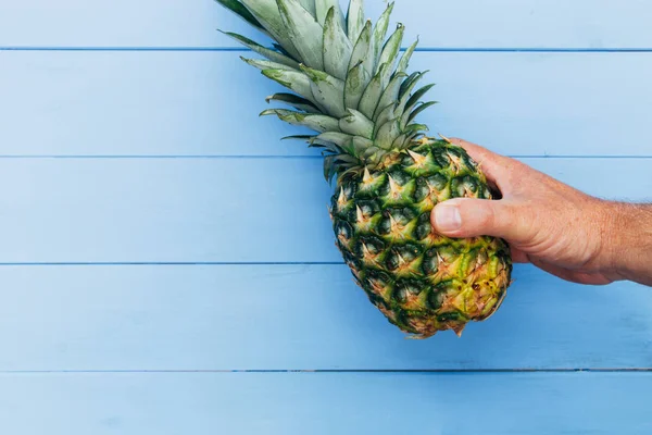 Ananasfrucht Der Hand Gehalten Auf Blauem Holztischhintergrund — Stockfoto