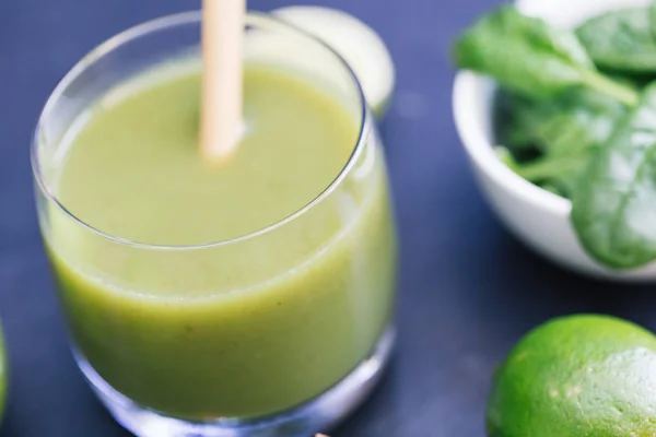Green smoothie drink with straw on dark background closeup