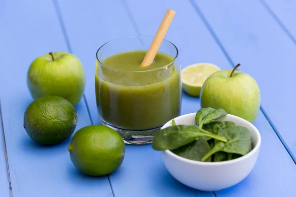 Healthy green smoothie drink with straw on blue table background