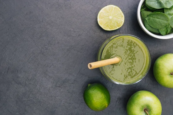 Green smoothie drink with straw on dark background with copy space