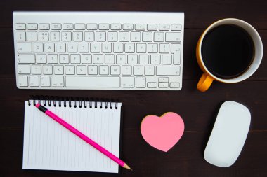 Bilgisayar klavye, kahve fincanı, kalem, Not defteri, pembe kalp ve ahşap ofis resepsiyon çalışma alanında fare