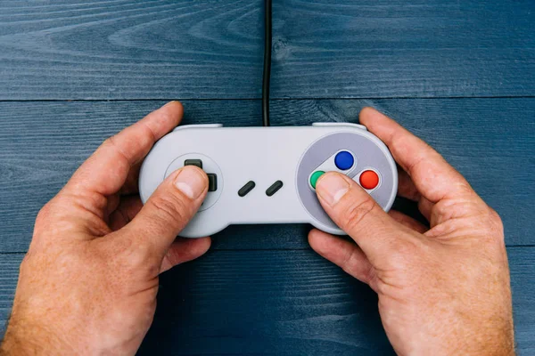 Man playing retro video game with controller on dark background