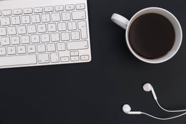 En az ofis resepsiyon bilgisayar klavye kahve müzik kulaklık koyu arka plan üzerinde