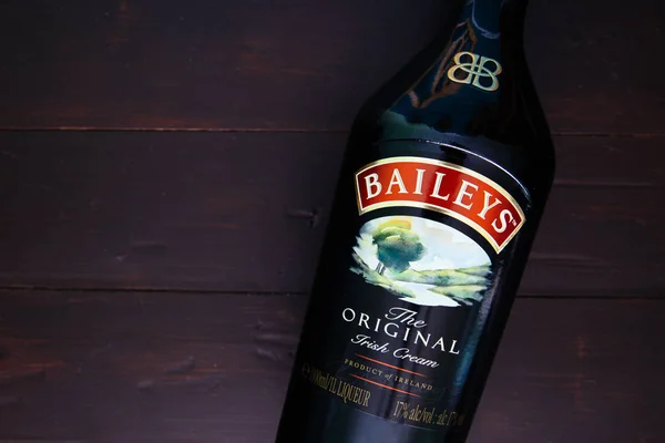 Londra - 08 Ocak 2019: Baileys İrlanda Kreması cam şişe koyu ahşap arka plan üzerinde
