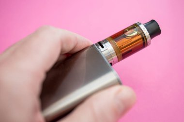 Vape kalem metal elektronik sigara vaping pembe arka plan ile tutan adam