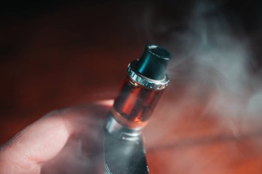 Dostum holding vape kalem vaping duman bulutu koyu arka plan ile metal elektronik sigara