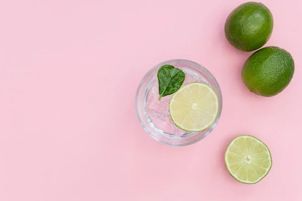 Gin tonic cocktaildrink i glas på sommaren rosa bakgrund — Stockfoto