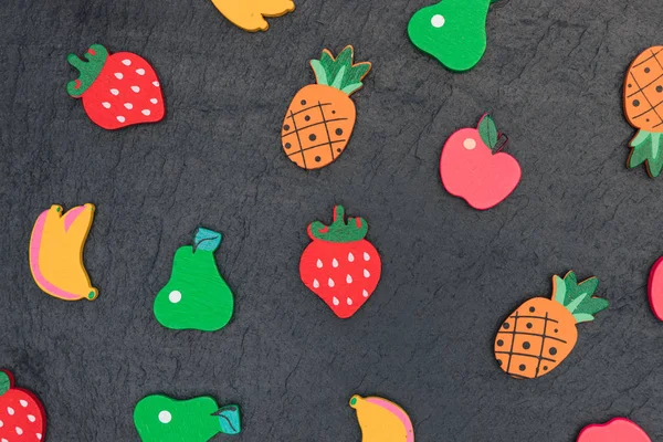 Wood fruit shapes on dark minimal summer food background