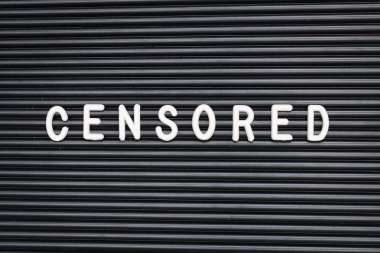 Koyu siyah arka plan üzerinde sansürlü metin kelime harfleri