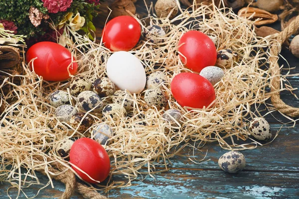 White chicken eggs, red eggs, quail eggs near dry flowers. Eggs For Easter.