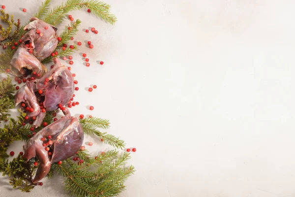 Wild hunting fowls in cooking. Ptarmigan, fir-tree branches and cowberry arranged on light background.