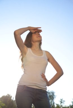 Gökyüzüne karşı duran ve bakmak güzel kadın. Güneşli gün