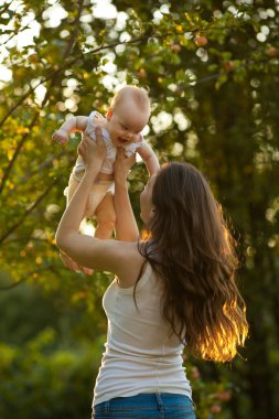Anne ve bebek dışarıda eğleniyor. Kollarındaki Holding bebek anne