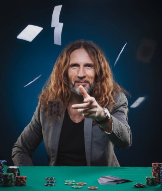Uzun saçlı yakışıklı adam bir casino poker oynamaya. Stüdyo kavramı mavi zemin üzerine