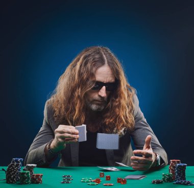 Uzun saçlı yakışıklı adam bir casino poker oynamaya. Stüdyo kavramı mavi zemin üzerine