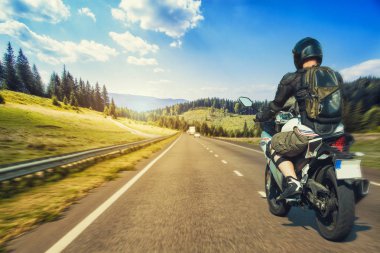 Motorcyclist rushes along the picturesque mountain highway. sport bike clipart