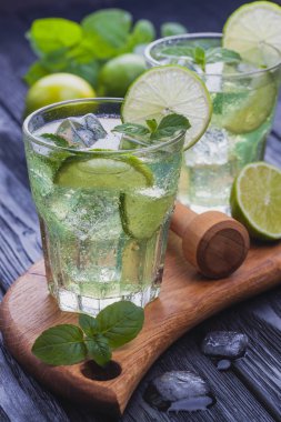 Siyah ahşap bir masa üzerinde buz ile soğuk mojito serinletici iki bardak