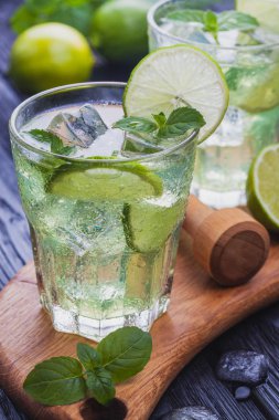 Siyah ahşap bir masa üzerinde buz ile soğuk mojito serinletici iki bardak